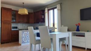 a kitchen with a white table and white chairs at Delizioso appartamento a Capalbio con vista in Capalbio