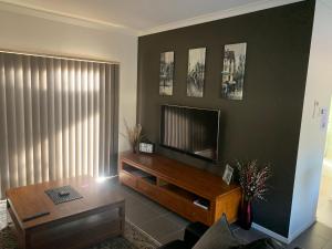 sala de estar con TV y mesa de centro en Elmsford Cottage en Warragul