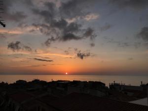 einen Sonnenuntergang über dem Wasser mit Häusern und Gebäuden in der Unterkunft Duomo Apartments Cefalù in Cefalú