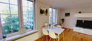 sala de estar con mesa blanca, sillas y ventanas en Central Apartments Chlebnicka 1 en Gdansk
