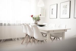 a white dining room with a white table and white chairs at Village Charme in Molini di Tures