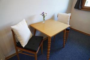 d'une table en bois avec deux chaises et un vase de fleurs. dans l'établissement Haus Alpenland, à Mariazell