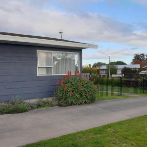 a blue house with a window and a bush with flowers at Family friendly unit in Hastings