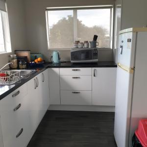 a kitchen with white cabinets and a white refrigerator at Family friendly unit in Hastings