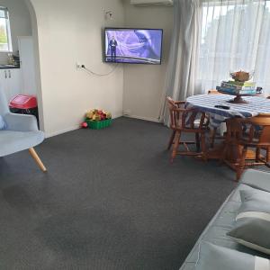 uma sala de estar com uma mesa e uma televisão na parede em Family friendly unit em Hastings