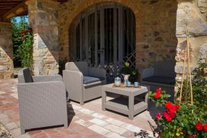 een patio met rieten stoelen, een tafel en bloemen bij Agriturismo Le Vigne in Monticiano