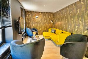 uma sala de estar com um sofá amarelo e cadeiras em Gatsby River II em Yvoir