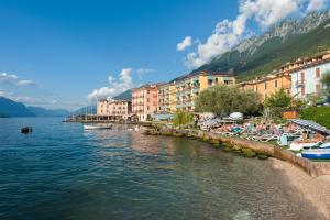 a beach with a group of buildings and a body of water at Hotel Nettuno in Brenzone sul Garda