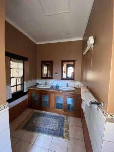a large bathroom with two sinks and two mirrors at Vintage Serene Villa in Hartbeespoort