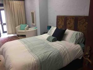 a bedroom with a large bed and a chair at Vintage Serene Villa in Hartbeespoort +40 photos