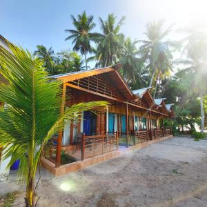 a house on the beach with palm trees at Lemon Grass Resort & Spa in Havelock Island