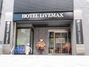 HOTEL LiVEMAX Tokyo Ayase-Ekimae في طوكيو: متجر أمام مدرج الفندق مع باقة من الزهور