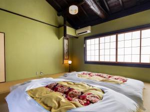 two beds in a room with green walls at naokonoza Bettei Umekoji in Kyoto