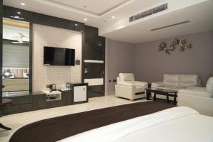 a bedroom with a bed and a tv and chairs at Royal Bliss in Patna