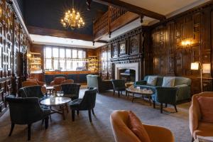 un restaurante con sillas, mesas y chimenea en The Billesley Manor Hotel en Stratford-upon-Avon