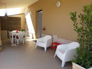 - un salon avec des chaises blanches, une table, une table et des chaises dans l'établissement Villa La fenice, à Granelli