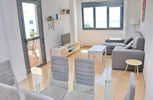 ein Wohnzimmer mit einem Sofa und einem TV in der Unterkunft Apartamento Río Salado in Conil de la Frontera