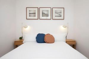 una camera da letto con un letto bianco con tre immagini sul muro di Fisa Rentals Aribau a Barcellona