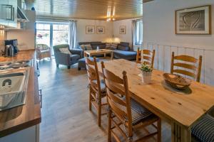cocina y sala de estar con mesa de madera y sillas en Seegras, en Nessmersiel