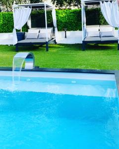 a swimming pool with two chairs and a swing at Hôtel Eden Cassis in Cassis