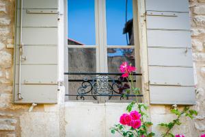 a window with a vase on a balcony with flowers at La Maison du Village in Saint-Rémy-de-Provence