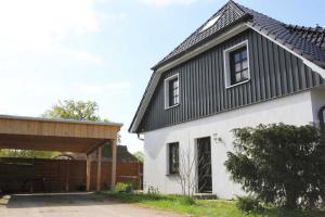 ein Haus mit einem schwarzen Dach und einem weißen Gebäude in der Unterkunft Oliver-Grolik in Born