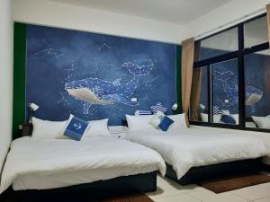 2 camas en una habitación con un mural de una ballena en Pier 10, en Magong