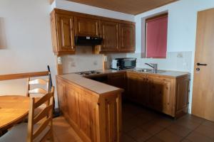 a kitchen with wooden cabinets and a sink and a table at Apartment Panorama Gerlitzen in Treffen