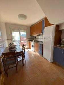 eine Küche mit einem Tisch und einem weißen Kühlschrank in der Unterkunft Apartamento Marexada Foz in Foz