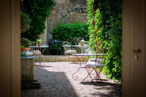 an outdoor patio with tables and chairs and plants at La Maison du Village in Saint-Rémy-de-Provence