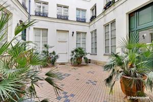 einen Innenhof mit Pflanzen vor einem weißen Gebäude in der Unterkunft CMG - Place des Vosges / Turenne in Paris