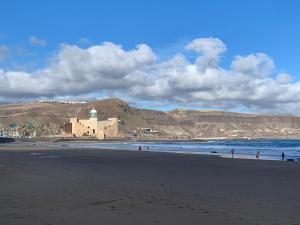 een strand met mensen die op het zand en de oceaan lopen bij KYO Surf Hostel in Las Palmas de Gran Canaria