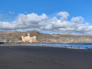 a beach with people walking on the sand and the ocean at KYO Surf Hostel in Las Palmas de Gran Canaria