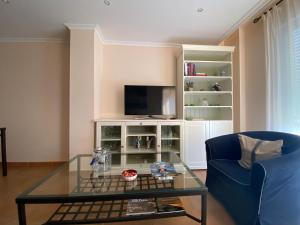 a living room with a glass table and a tv at Apartamento Marexada Foz in Foz