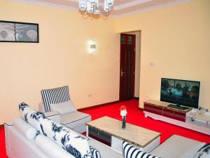 a living room with white furniture and a flat screen tv at Monalisa Hotel in Mtwapa