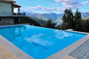 a large blue swimming pool with a view of mountains at Recanto do Escalheiro in Vieira do Minho