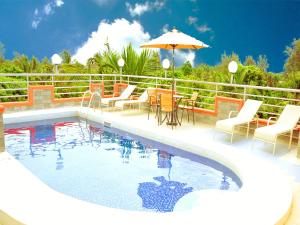 a swimming pool with chairs and a table and an umbrella at Monalisa Hotel in Mtwapa