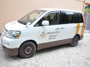 Monalisa Hotel في متوابا: سيارة فان بيضاء صغيرة متوقفة على شارع