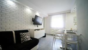 uma sala de estar com um sofá e uma TV em uma parede de tijolos em Apartamenty EverySky - Konstytucji 3 go Maja 66-1 em Karpacz