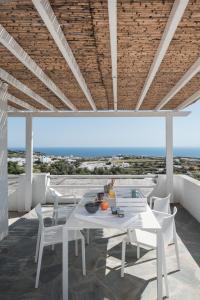 une salle à manger blanche avec une table et des chaises dans l'établissement NiMa Sifnos Residences, à Apollonia