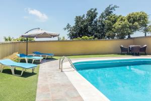 a swimming pool with two chairs and an umbrella at Buhardilla Armonia Rural in Granadilla de Abona