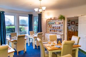 een eetkamer met tafels, stoelen en ramen bij Aquila Heights Guest House in Dorchester