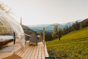 a bed and a chair on a deck with a view at Bubble-Suite in Graubünden in Versam