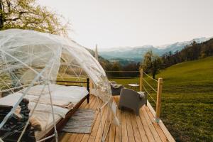 ein Bett auf einer Holzterrasse mit einem klaren Zelt in der Unterkunft Bubble-Suite in Graubünden in Versam