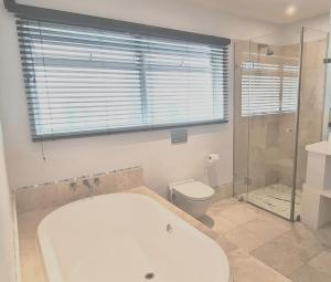 a bathroom with a tub and a toilet and a shower at Finchley Guesthouse in Cape Town