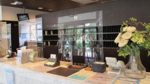 Toyoko Inn Naha Omoromachi Ekimae في ناها: كاونتر متجر مع إناء من الزهور عليه