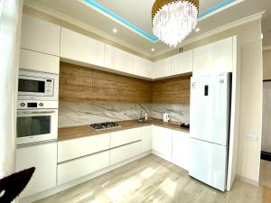 une cuisine avec des appareils électroménagers blancs et un lustre dans l'établissement ЖК ZAMAN, 2-комнатная квартира, à Atyraū