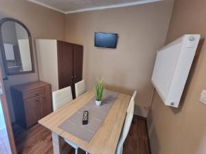 ein Esszimmer mit einem Tisch und einem TV an der Wand in der Unterkunft Ranczo Róż Wi-Ta in Przytór