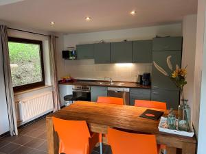 una cocina con mesa de madera y sillas naranjas en Ferienwohnungen Willingen Wald, en Willingen