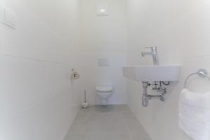 a white bathroom with a sink and a toilet at Apartments Oasis Wörthersee neu & zentral in Krumpendorf am Wörthersee